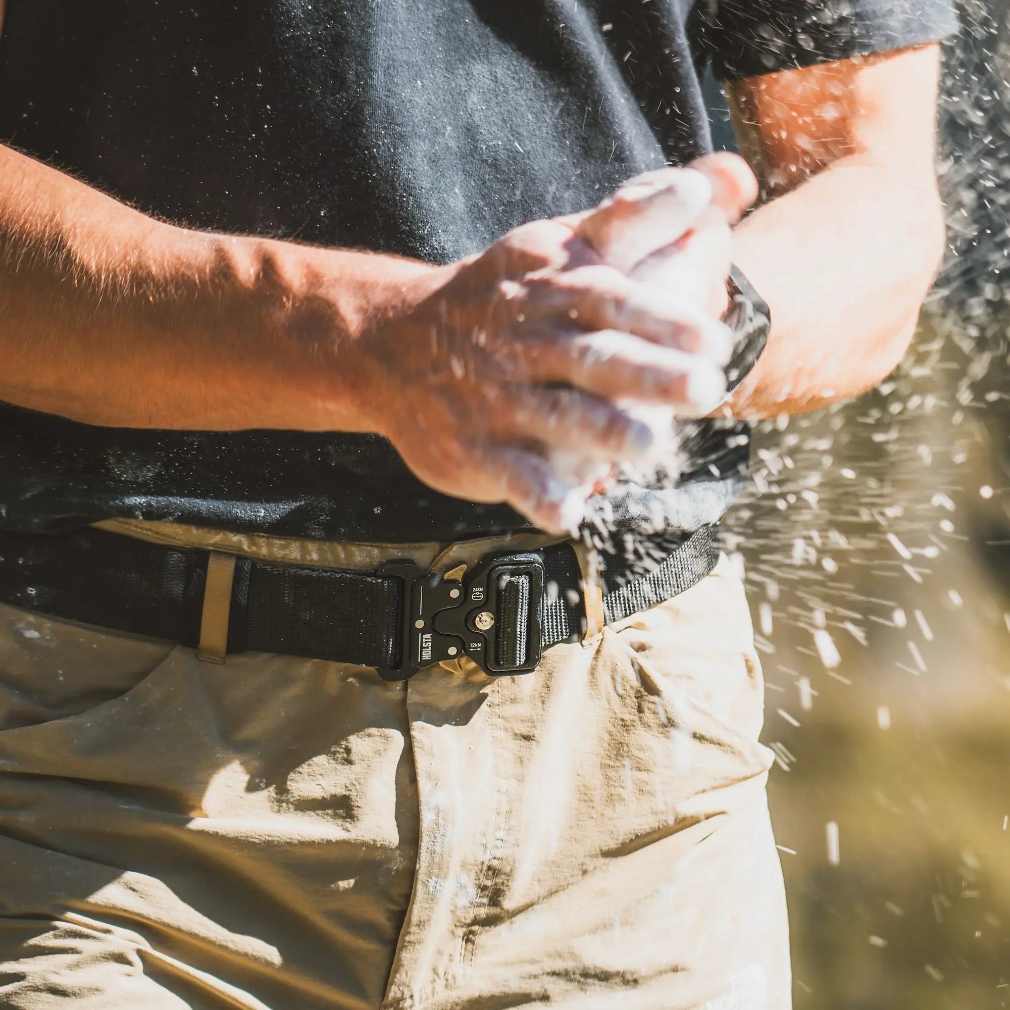 Lower torso of climber dusting chalky hands while wearing Holsta Belt