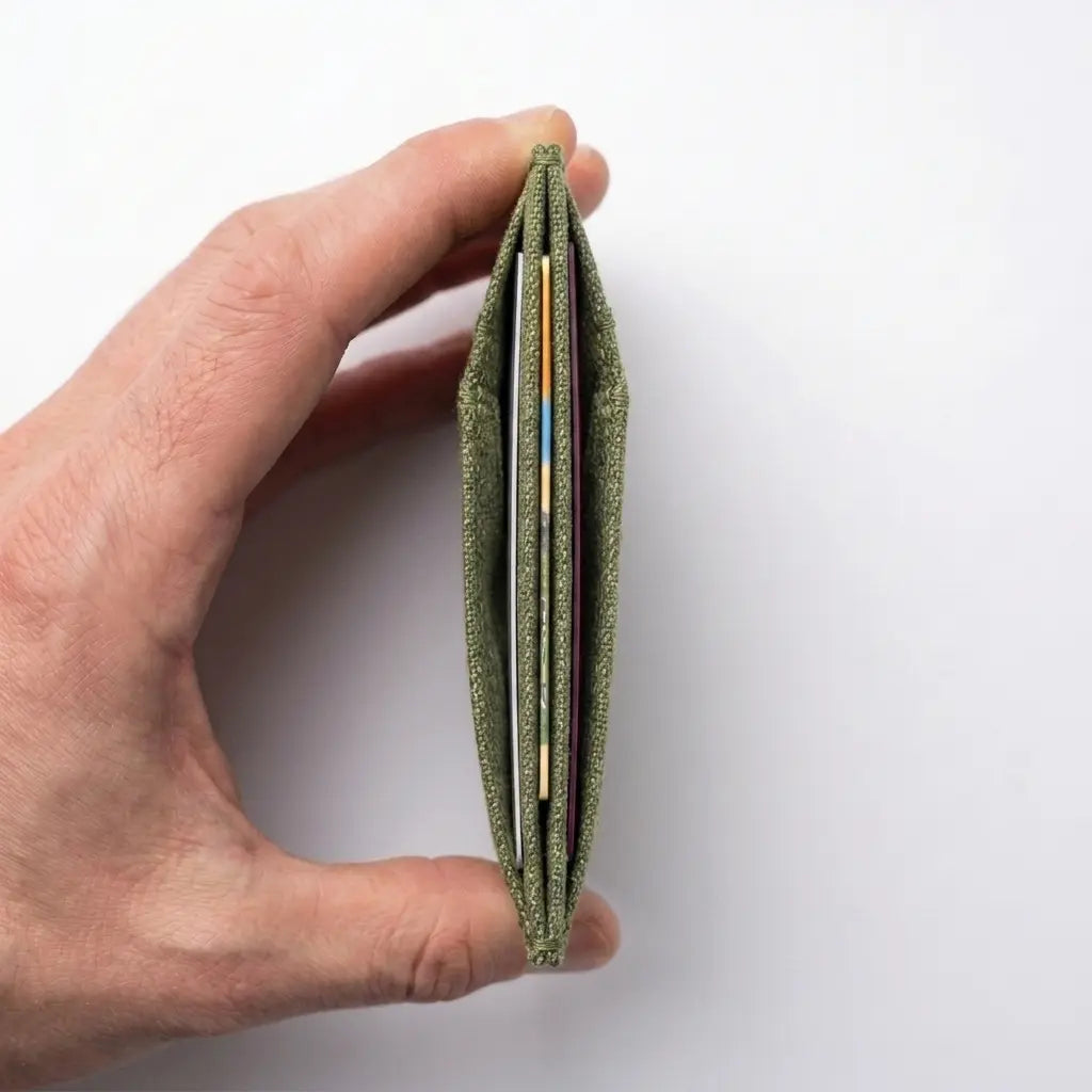 Hand holding a green wallet with cards on a white background